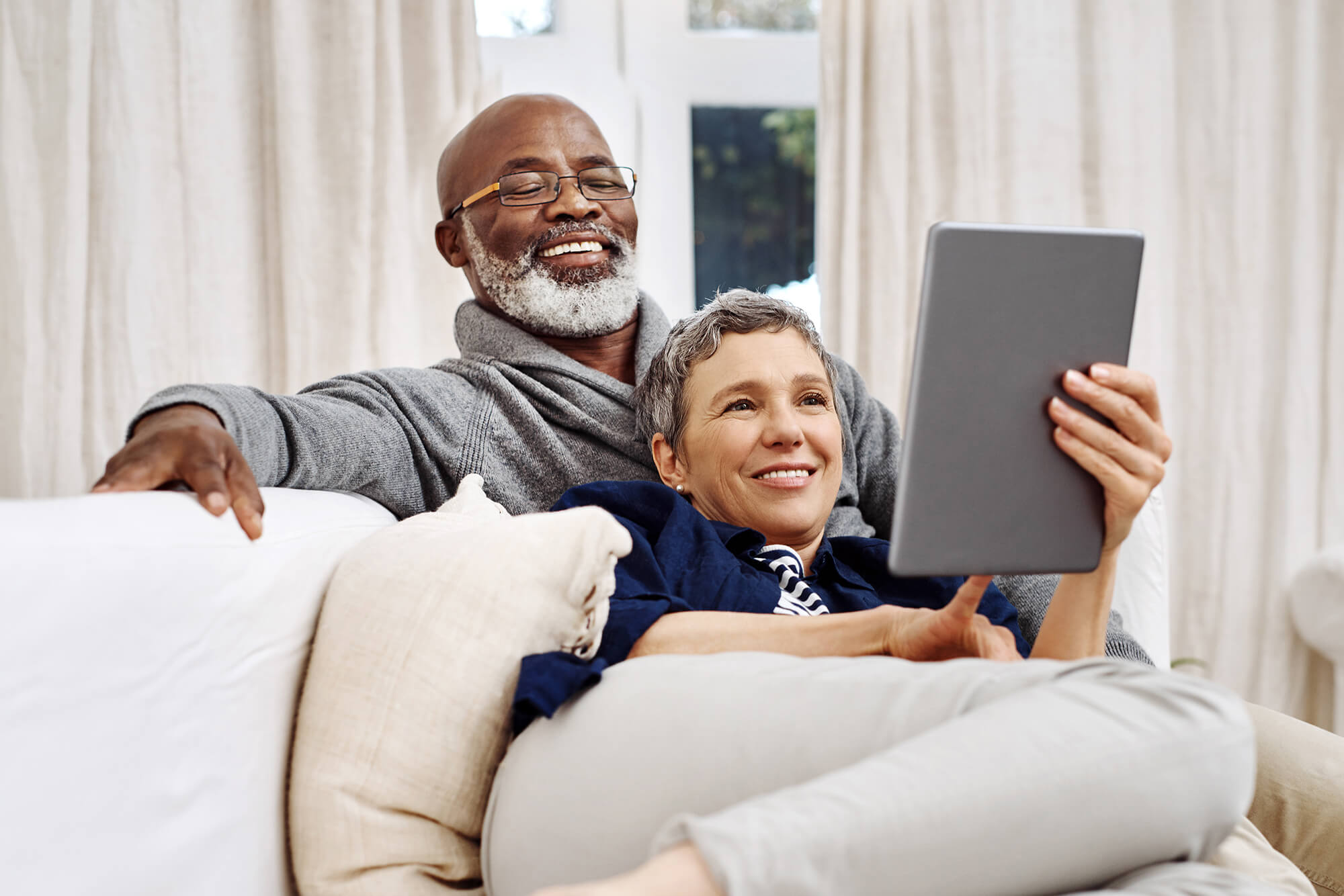 Senior couple using a tablet while relaxing on the sofa at home